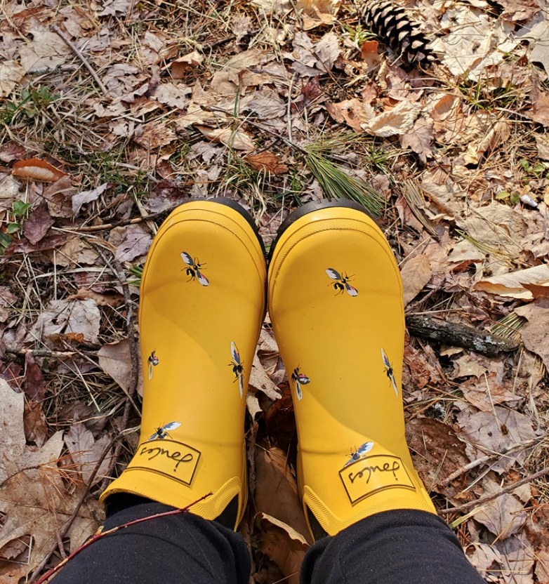 a reviewer wearing the bee patterned rain boots