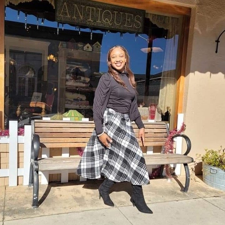 a reviewer wearing the skirt in black and white with a black long sleeve shirt tucked in 