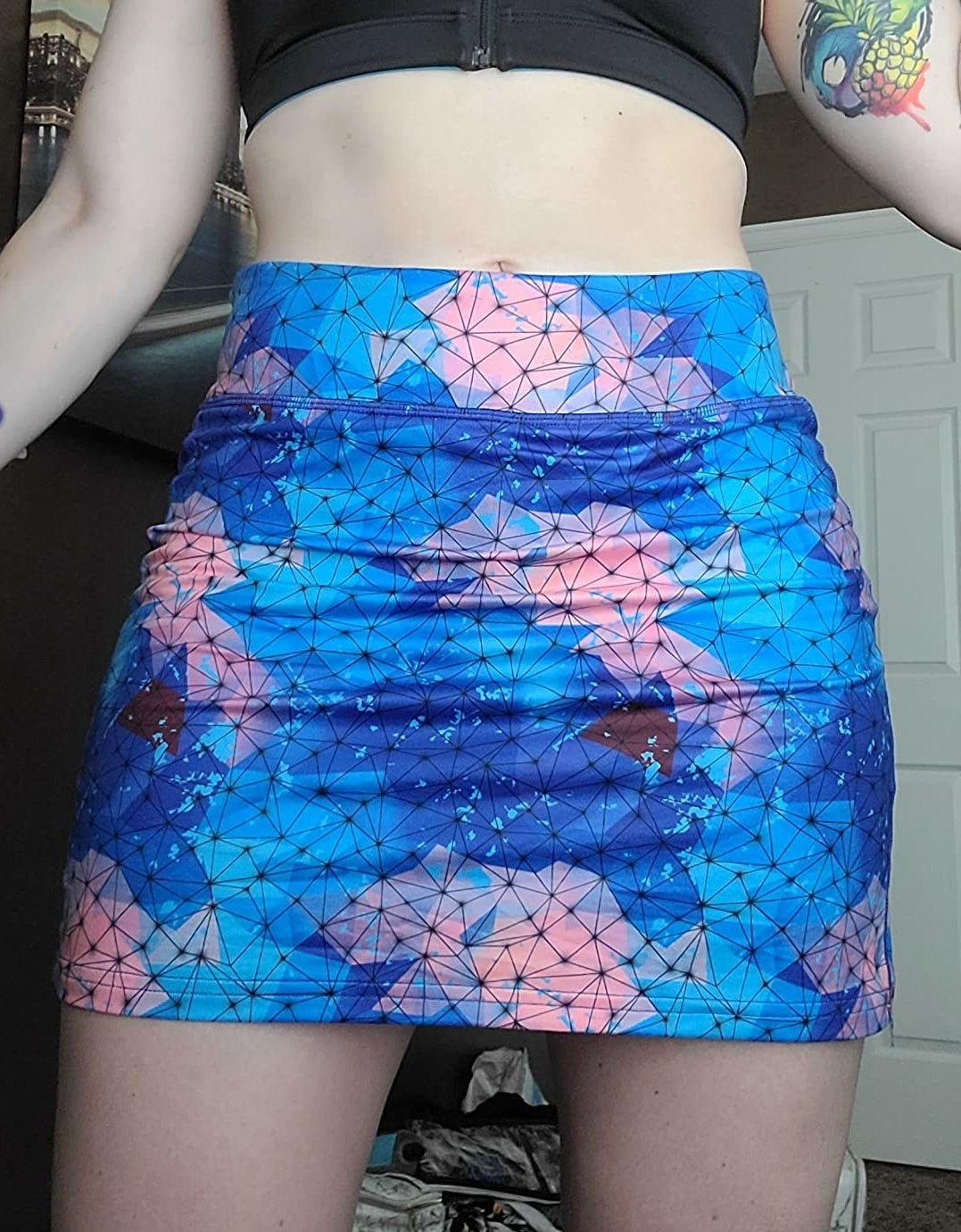 a reviewer wearing the skirt featuring a blue and pink abstract print 