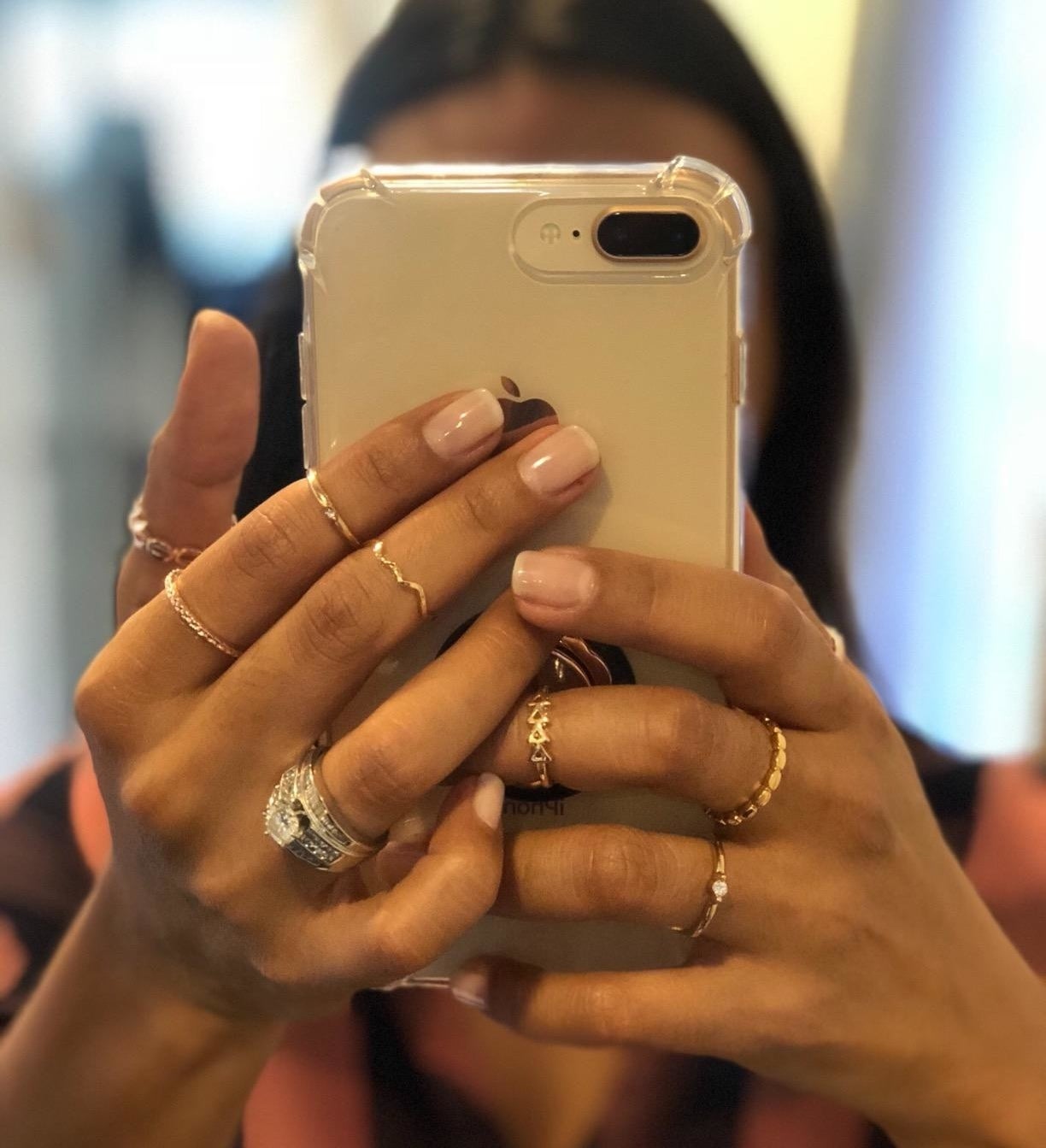 Reviewer is holding their camera up to a mirror to show off the stacked rings on their hands