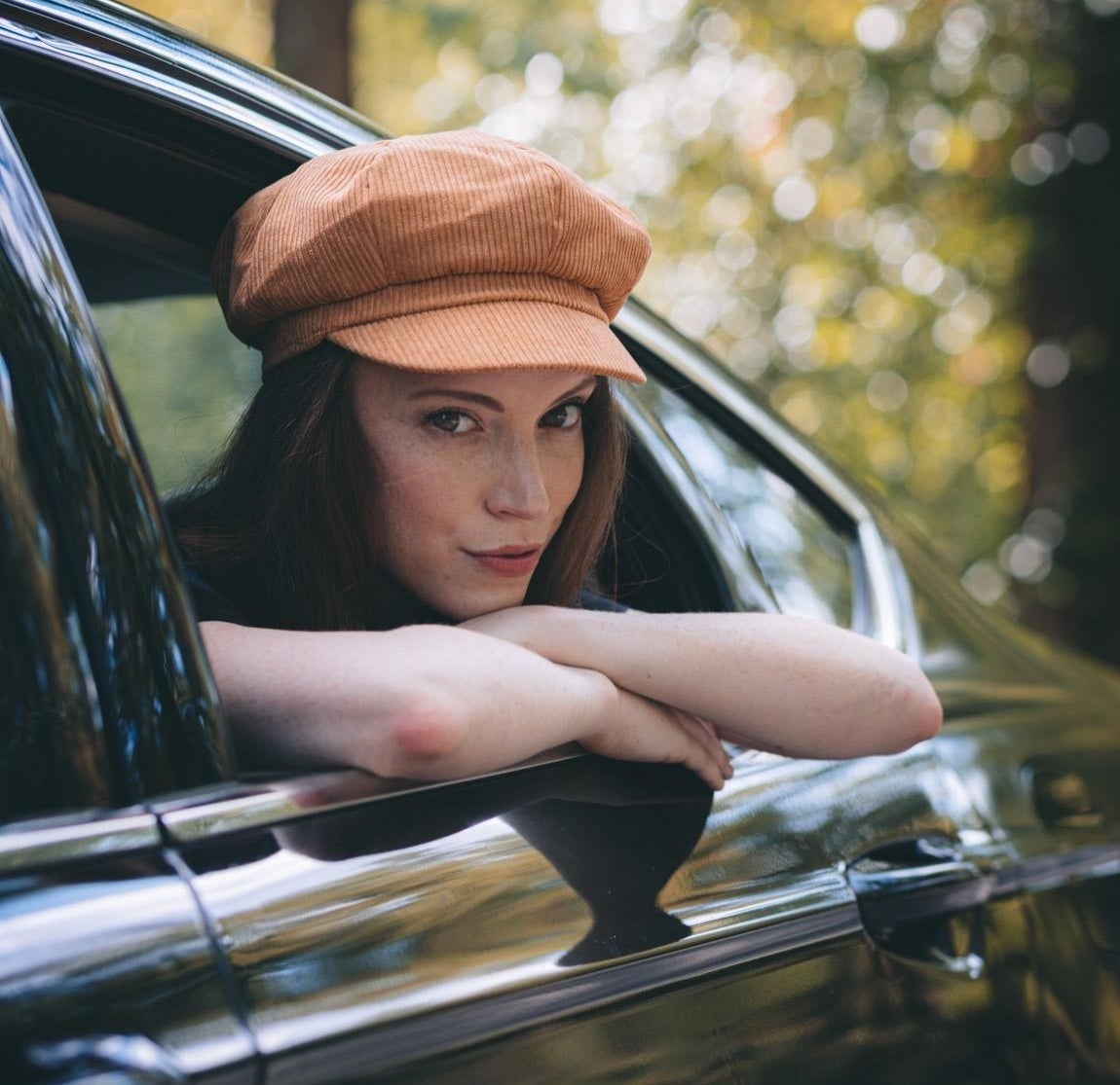 Reviewer is leaning out of a car window wearing a corduroy messenger cap