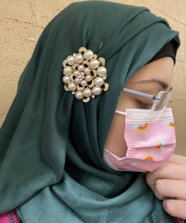 Reviewer is wearing a brooch pinned to their green hijab