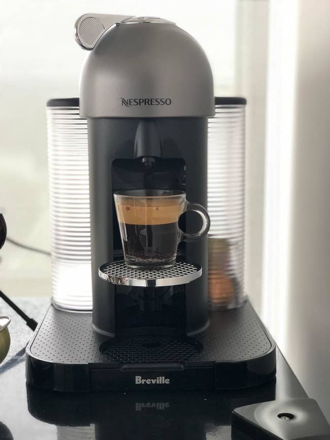 A reviewer's grey coffee maker brewing an espresso