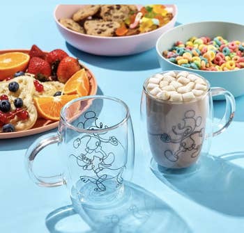 two glass mugs with an outline design of mickey and pluto on them