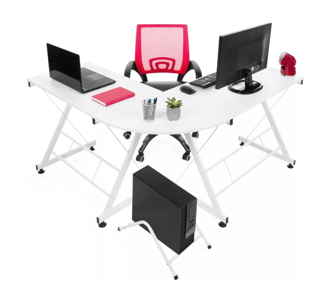 White L-shaped desk with pink chair, lap-top and desk top