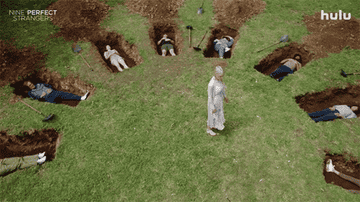 Masha standing in the center of the retreaters lying in a circle of graves