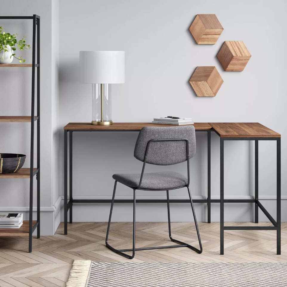 Dark wooden L-shaped desk with black legs, gray chair in front