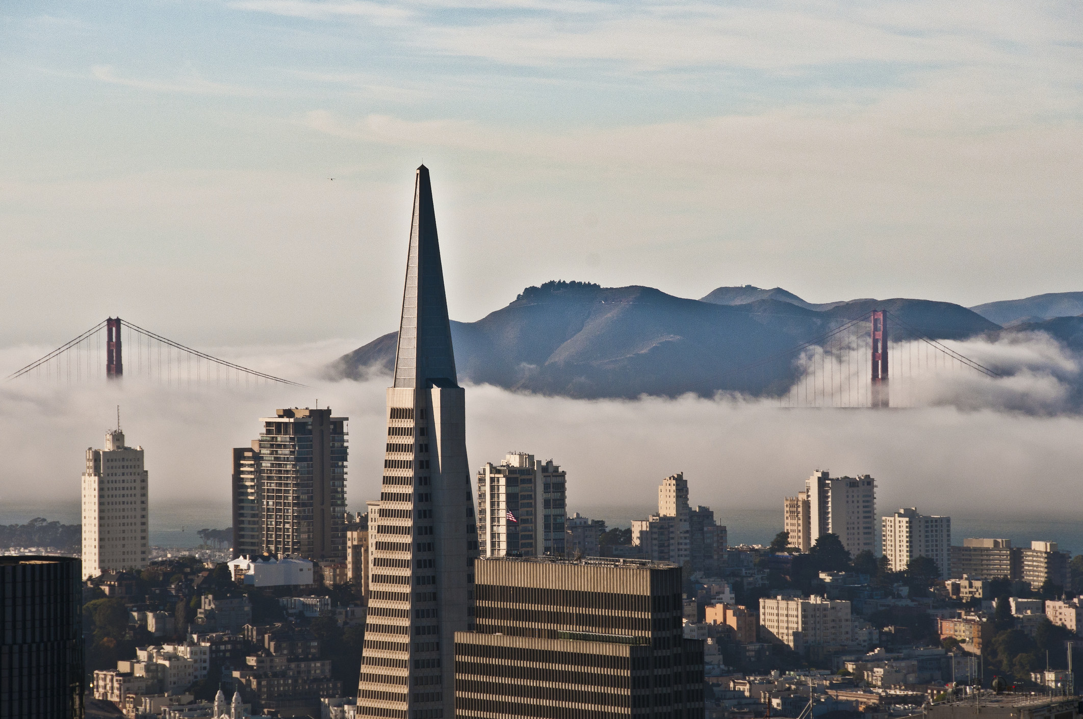 Fog rolling in to San Francisco skyscrapers with the Golden Gate Bridge in the distance