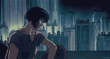 Major Motoko Kusanagi sat by the window the city skyline behind her as her hair blows in the wind.