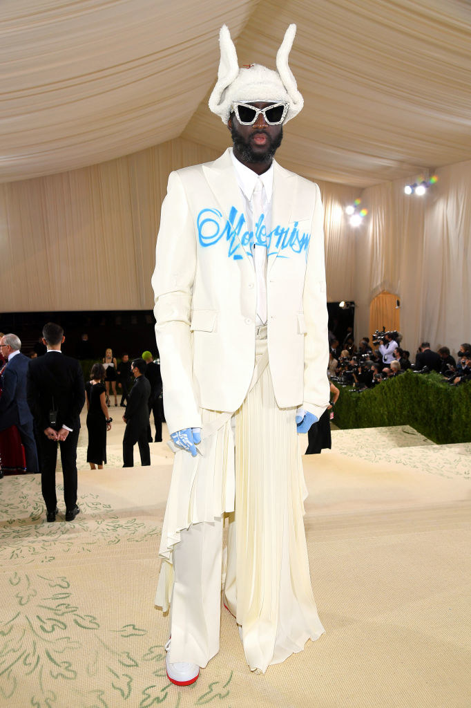 Virgil Abloh wears a light colored suit and jacket with a sheer train coming from the belt of the slacks