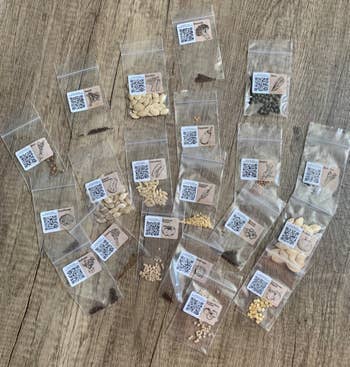 Assorted seed packets arranged on a wooden surface, each labeled with a QR code and seed type for easy shopping