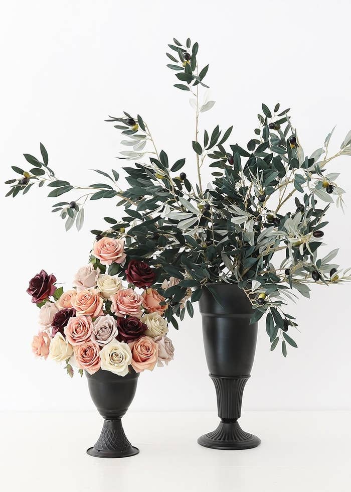 two urn-like black metal vases holding bouquets