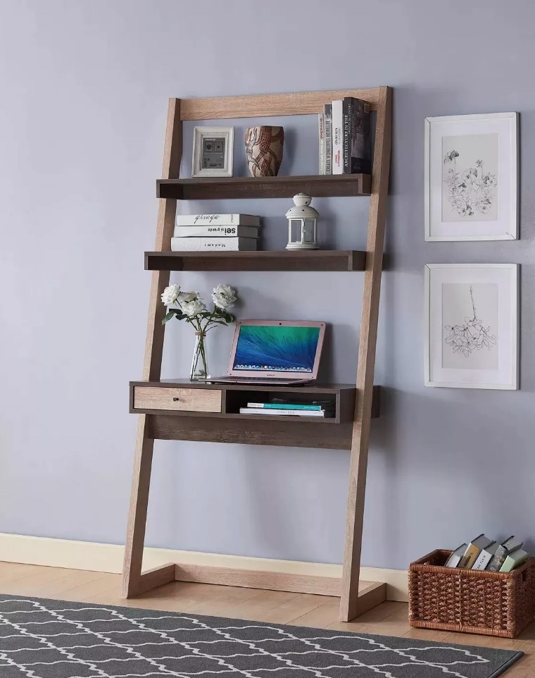 Wooden leaning desk with cubby and drawer desk top, and two top shelves with books and decorative items