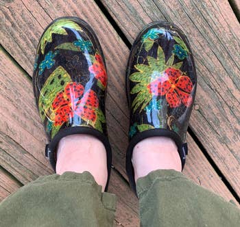 Reviewer's black clogs with green leaves and red flowers are shown on a deck