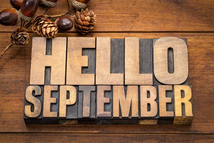 Hello September - word abstract in vintage letterpress wood type blocks against grunge wooden background with a fall decoration