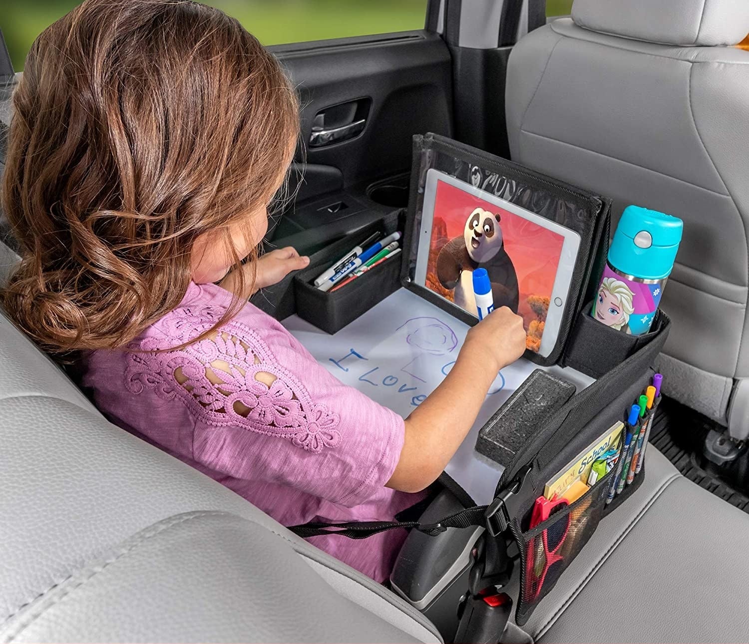 A model watching the tablet and coloring on the table in a car