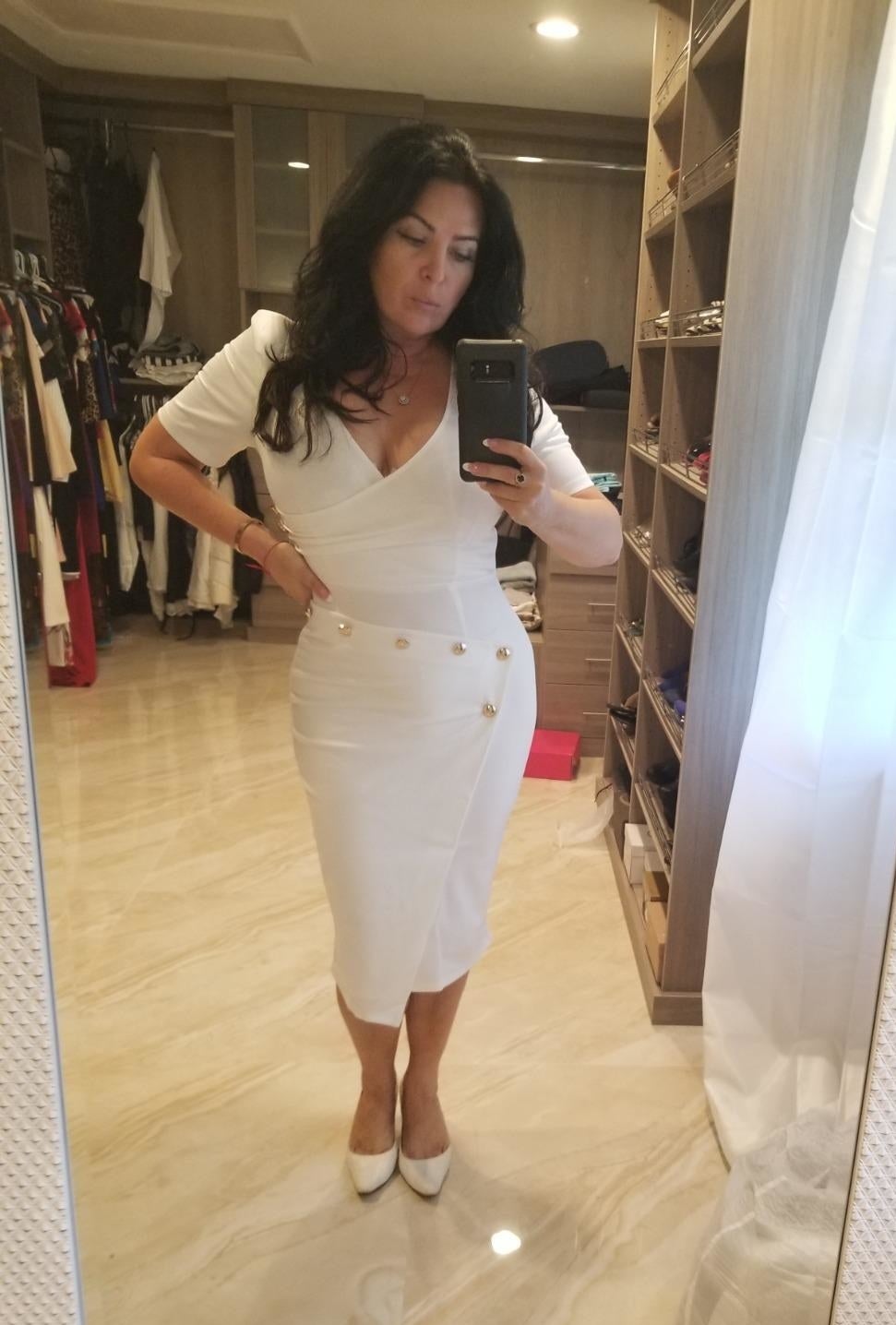reviewer wearing the white dress with gold stud details
