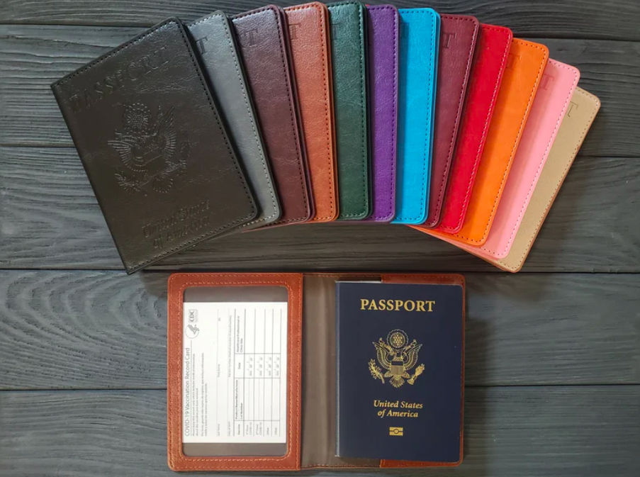 An image of a variety of the vaccine passports in multiple colors with one of them open showing where your passport and vaccination card fit