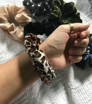 reviewer with a leopard print scrunchie on their wrist and the others in the back in the background