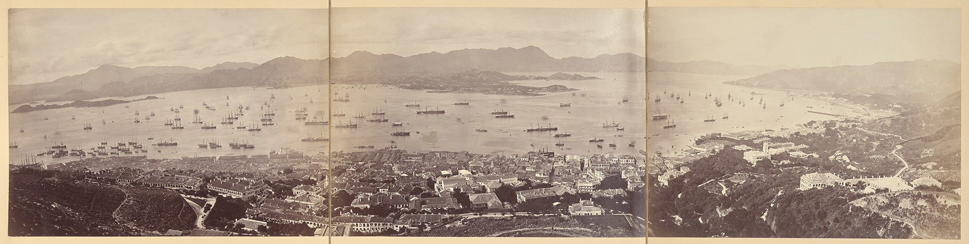 A panoramic view of Hong Kong Harbor, with several boats, ships, and other vessels on an expansive body of water, stitched together between three photos