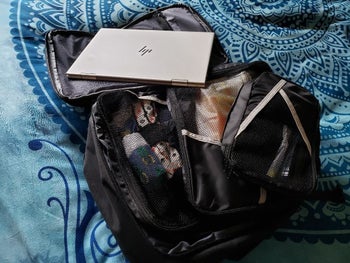 reviewer's backpack open and full of packing cubes and a laptop