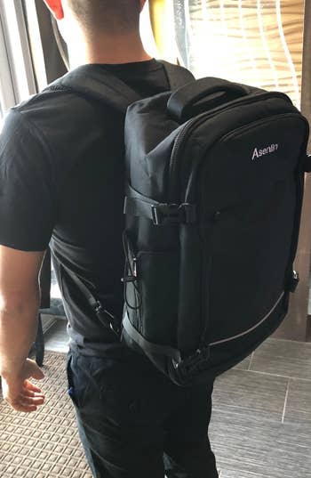 reviewer wearing the travel backpack in black