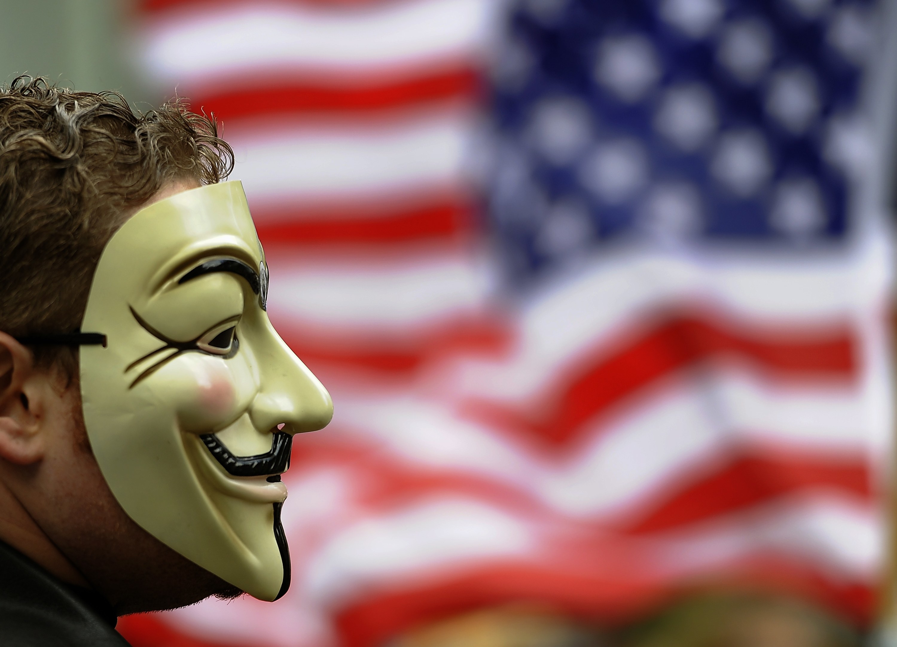 A masked protester in front of a flag during Occupy Wall Street