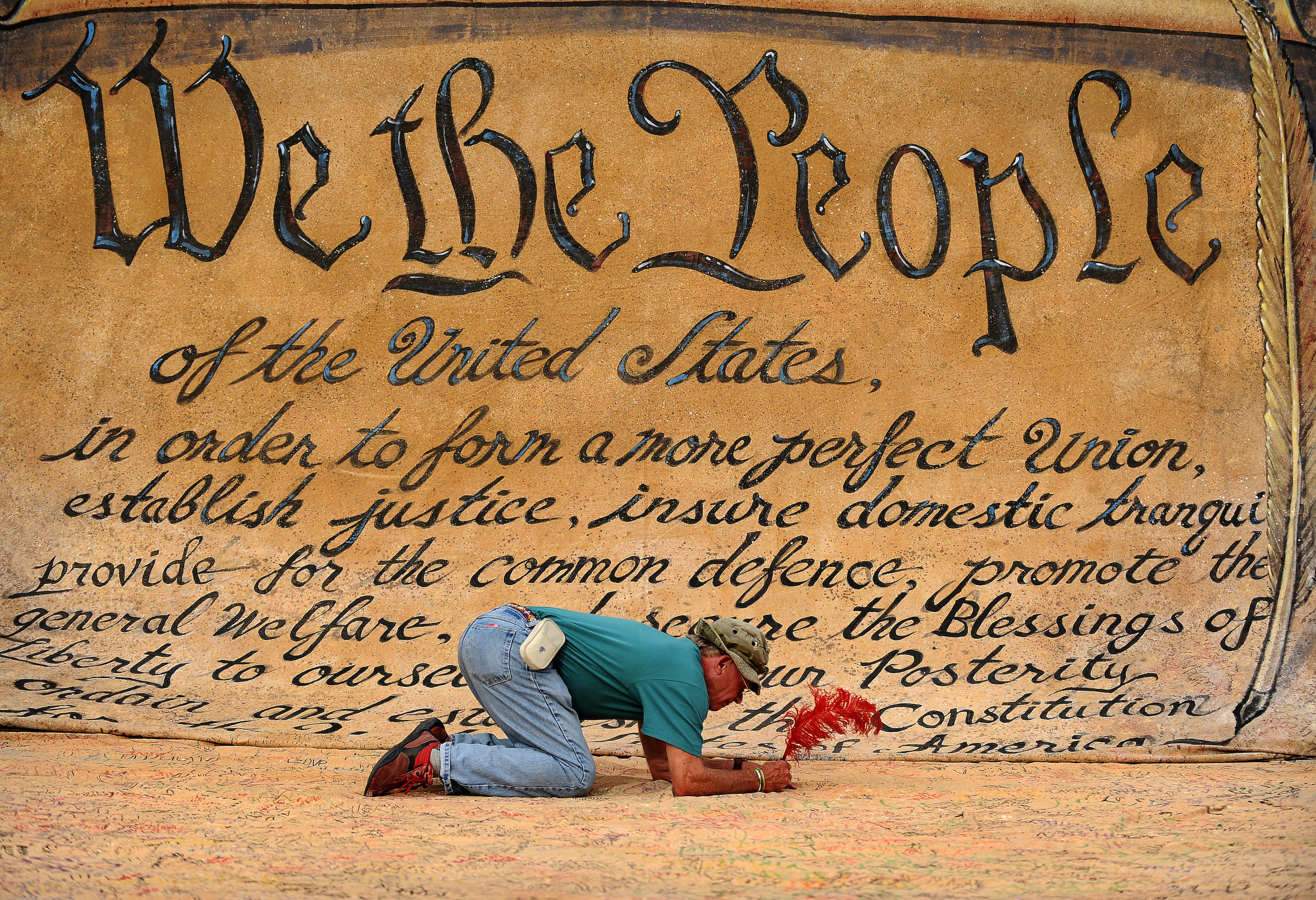 A man signs a large drawing of the Constitution at a protest in Washington, DC