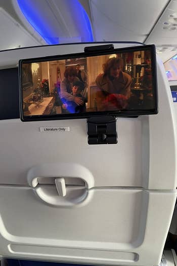 reviewer's phone playing a movie and clipped to a closed airplane tray table