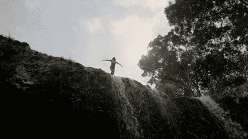 Someone diving off a waterfall cliff into the water below