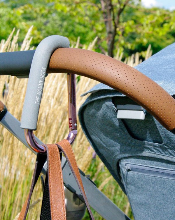 A stroller with a large carabiner hook attached to it with a purse suspended from the hook