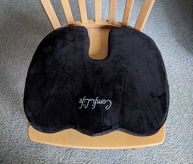 The black u-shaped cushion on a wooden chair