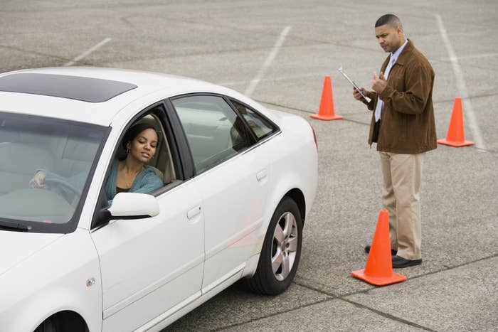 student driver driving through cones while an instructor watches and grades