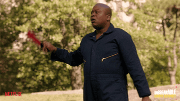 Titus Burgess fanning himself with a hand fan