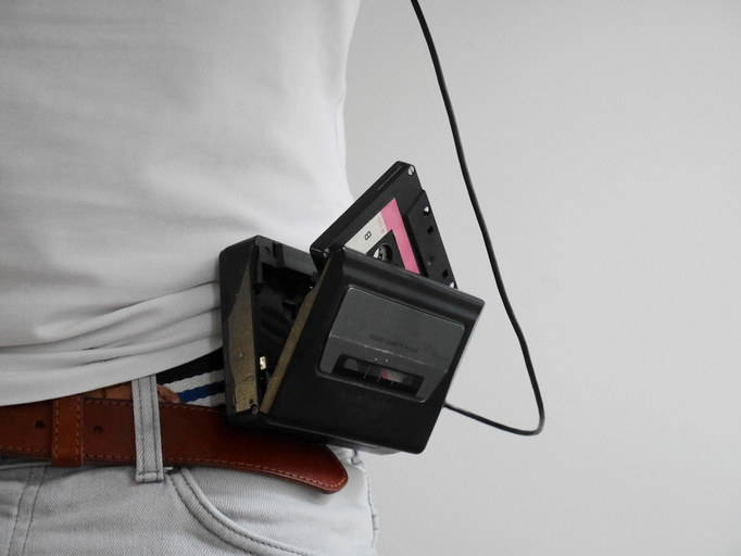 A portable cassette player latched on a person&#x27;s belt.