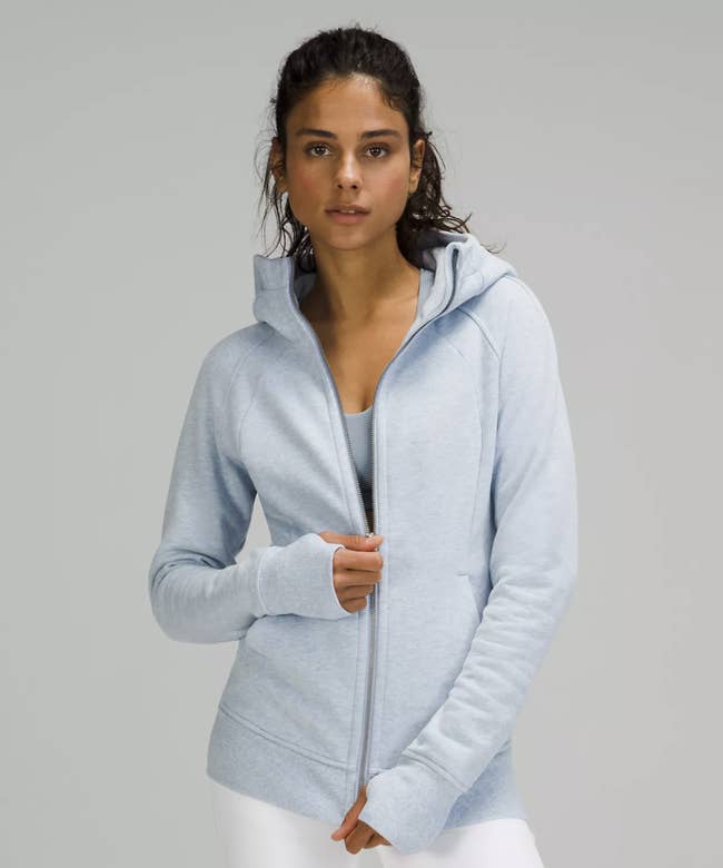 Model wearing pale blue zippered hoodie with thumb holes