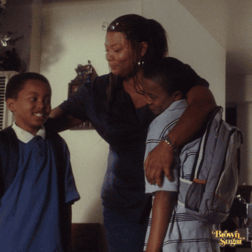 GIF of Queen Latifah as Francine in Brown Sugar hugging two young boys wearing school backpacks