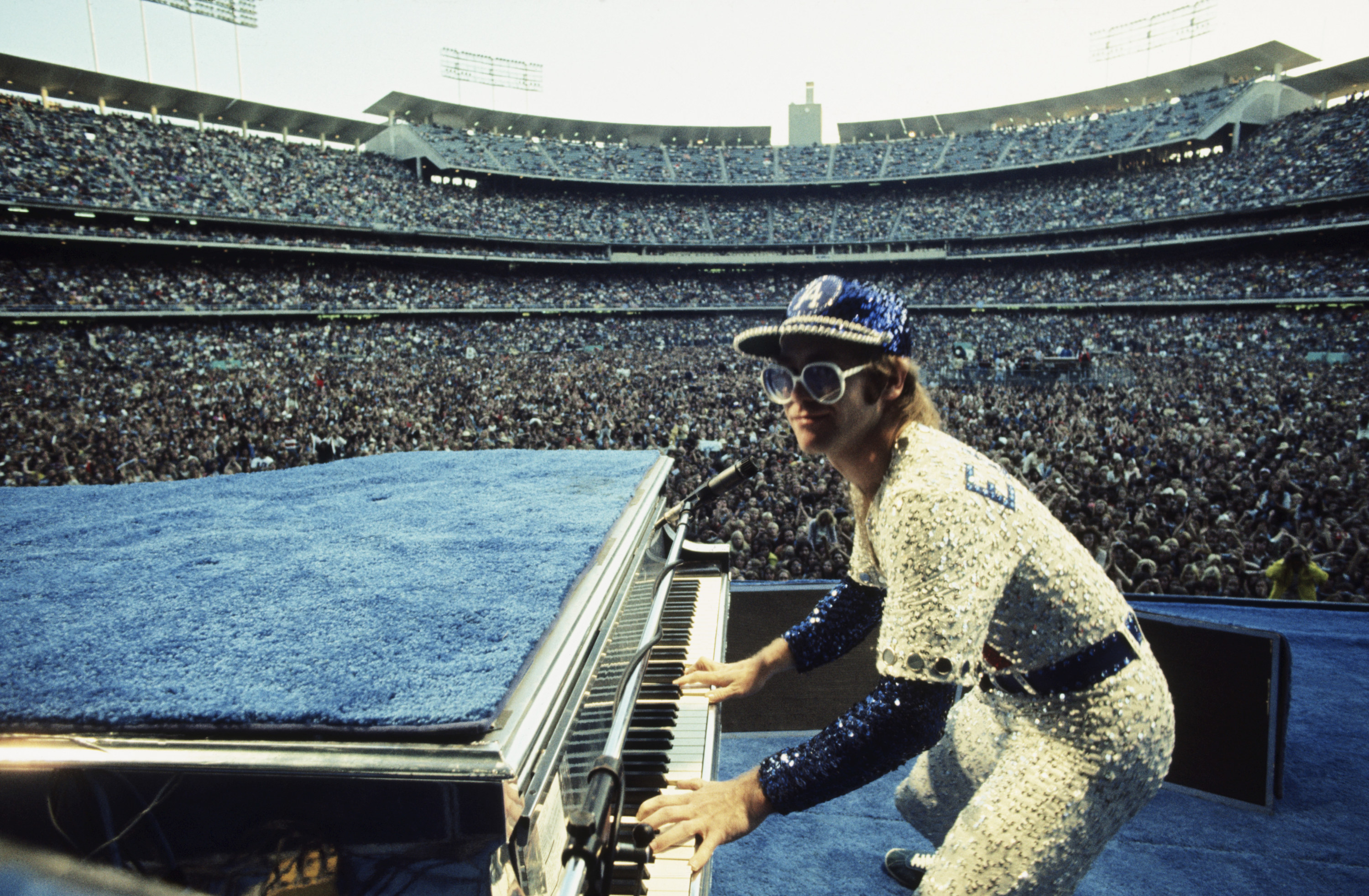 Elton John performing while wearing a jeweled baseball outfit