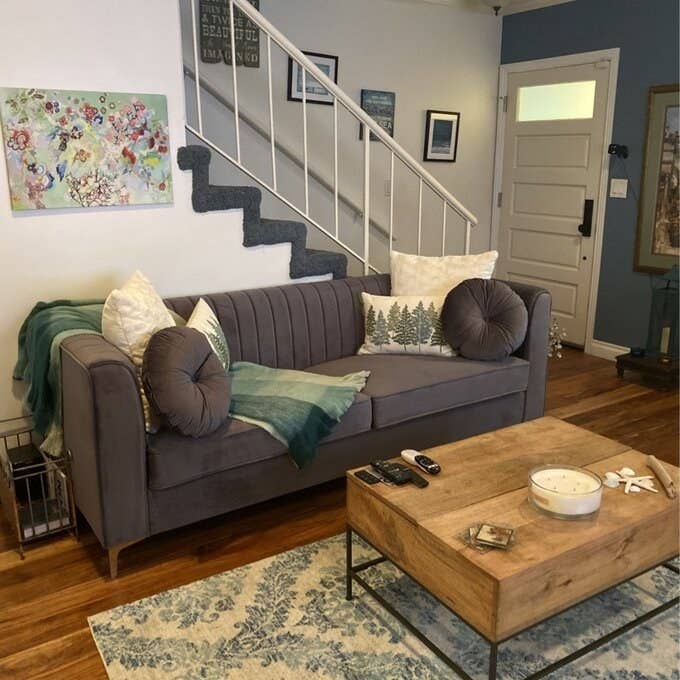 reviewer image of the gray couch with matching circle pillows and other white pillows on it in a living room with a wooden table