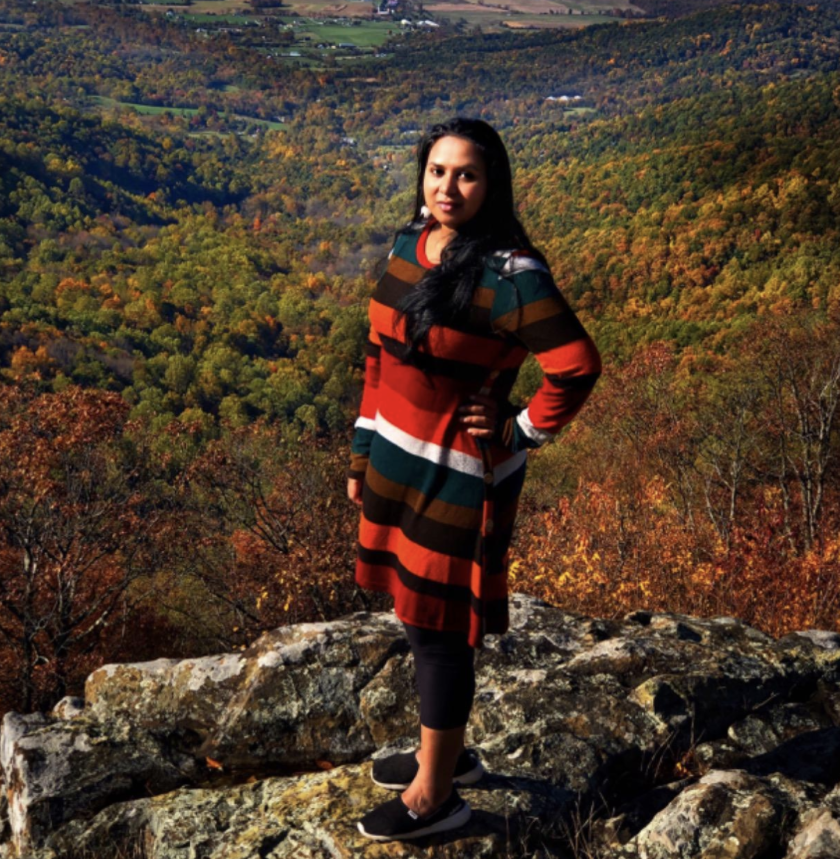 a reviewer wearing the multicolored striped dress in front of autumnal forest