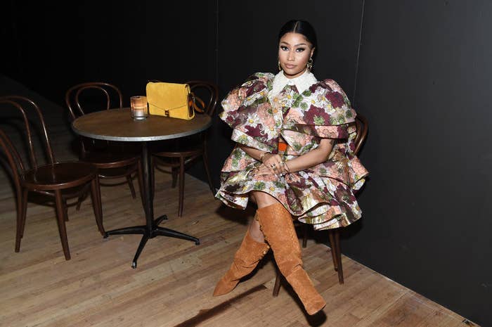 Nicki sitting at a table in a floral print dress with the Peter Pan collar and suede boots