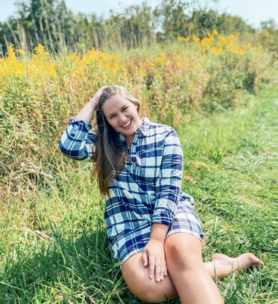 A customer review photo of them wearing the dress in blue plaid in a grassy field