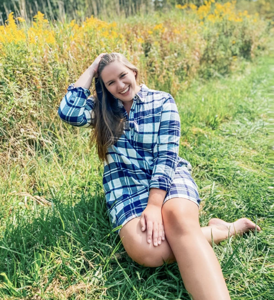 A customer review photo of them wearing the dress in blue plaid in a grassy field