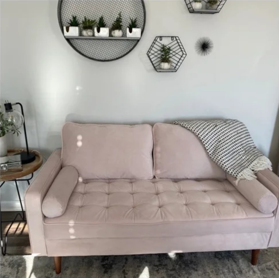 the pink couch with a throw blanket over it and wall decorations above it