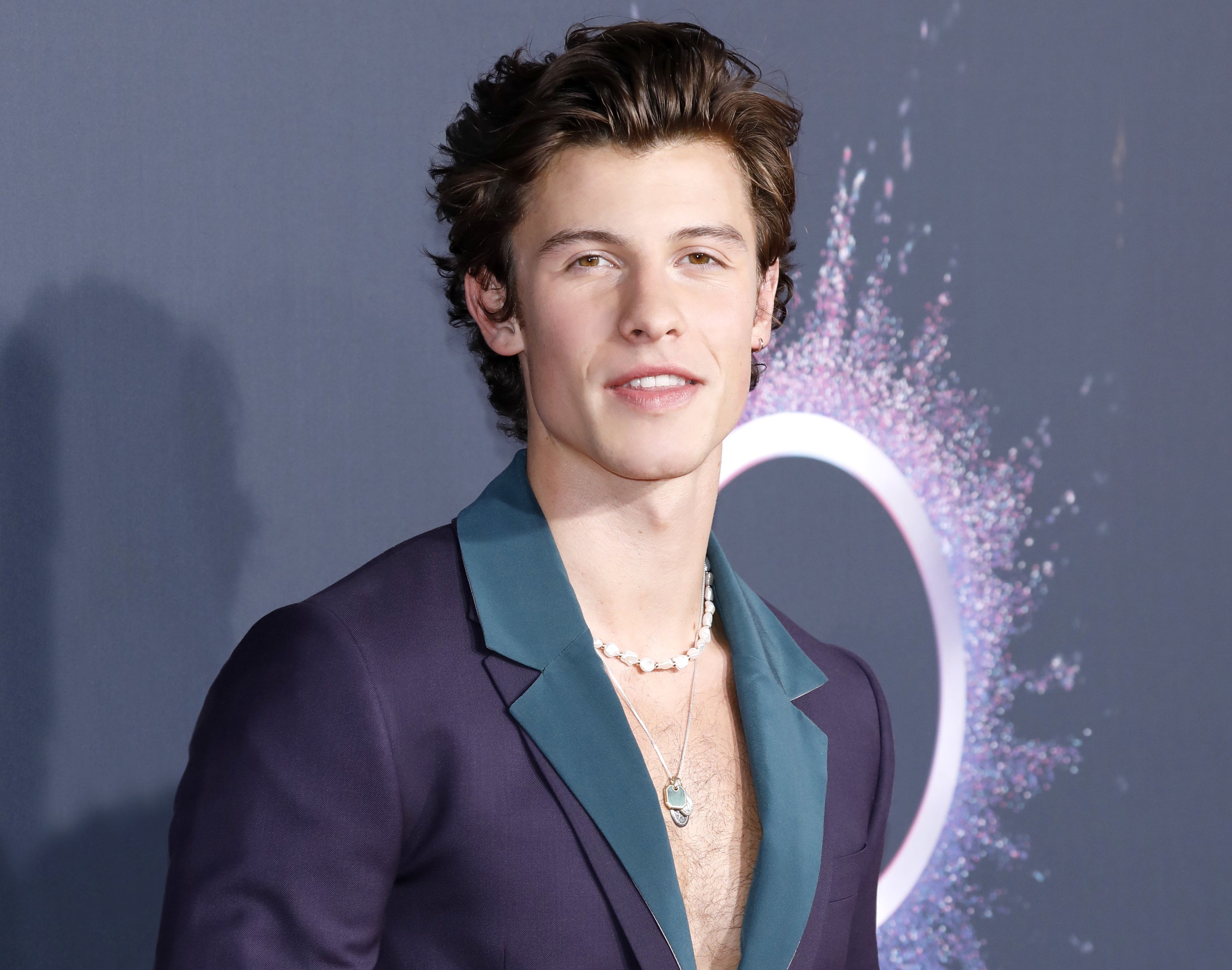 Shawn wears a purple suit jacket and teal button down