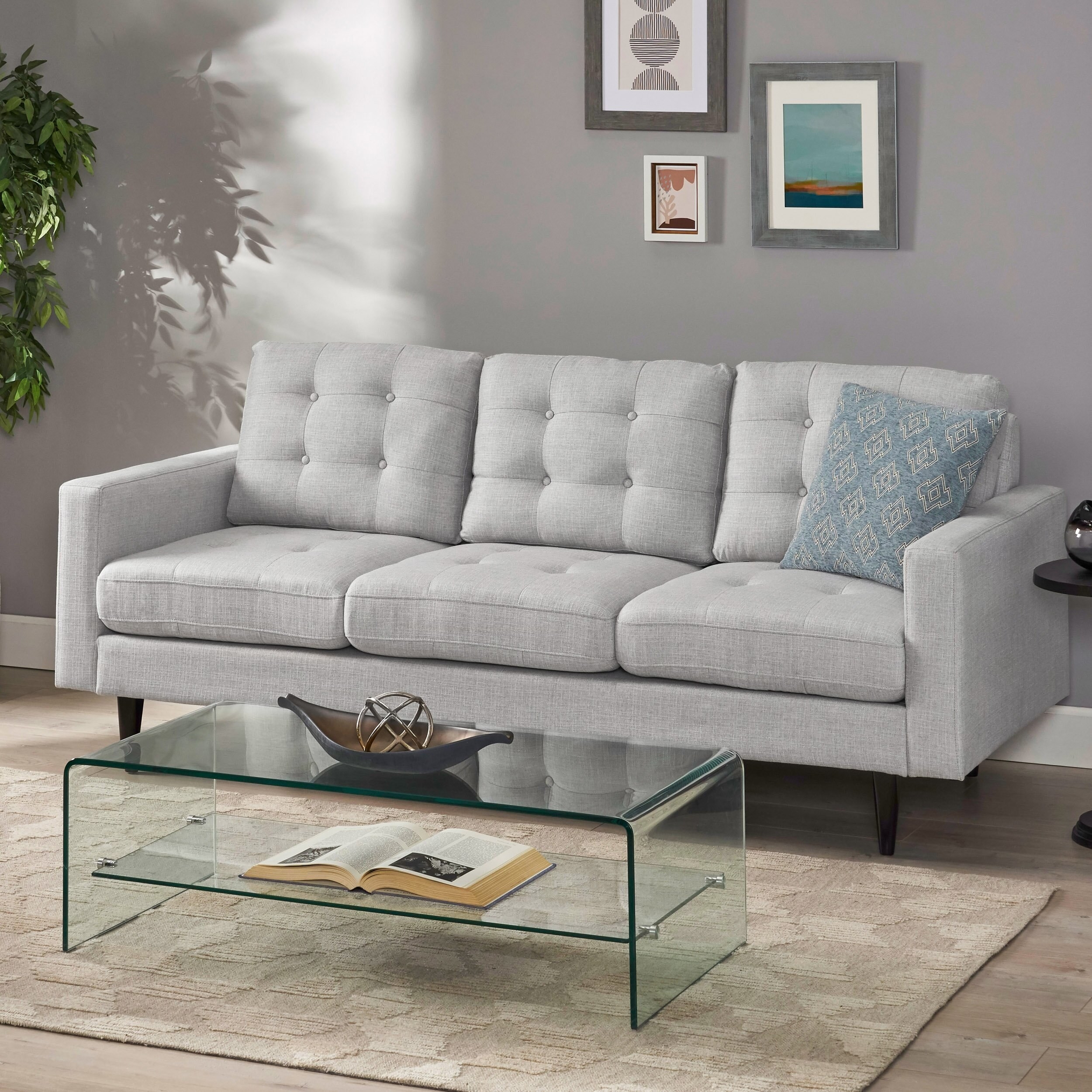 the sofa in gray with a glass coffee table in front of it