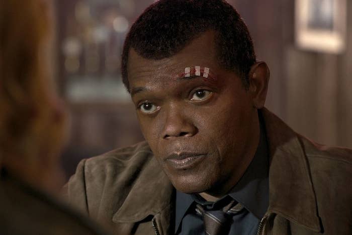 Nick Fury wearing a collar shirt, stripe tie, and suede jacket 