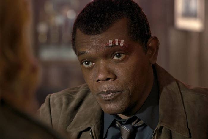 Nick Fury wearing a collar shirt, stripe tie, and suede jacket