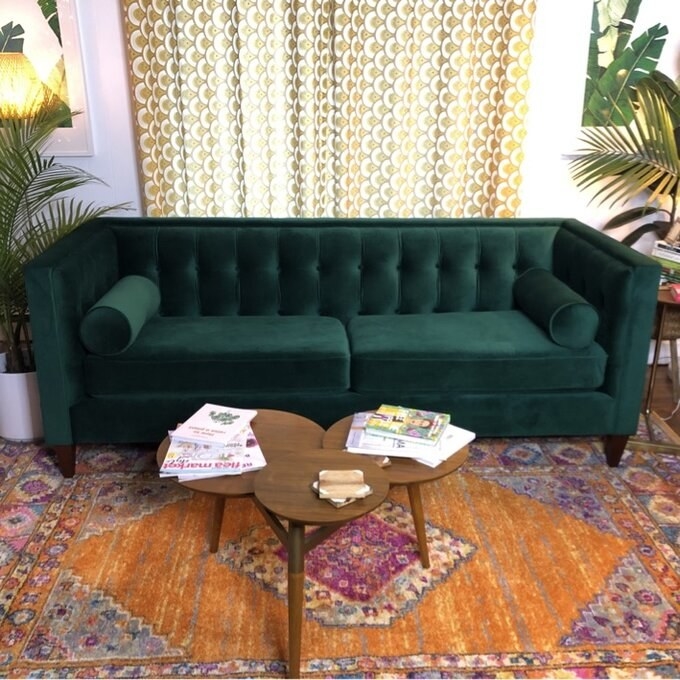 the green velvet couch on top of a colorful rug
