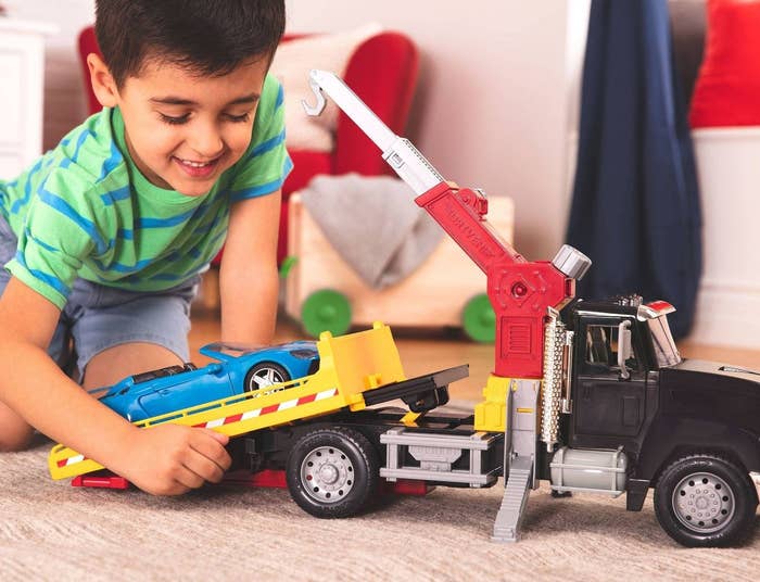 Kid playing with crane truck and car